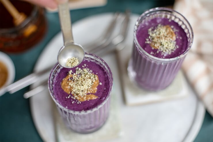 Hemp seeds being sprinkled on a purple smoothie