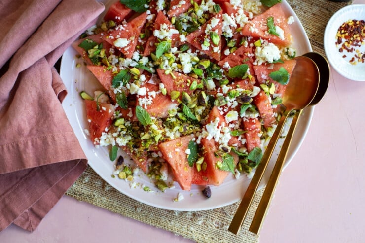 Platter of watermelon pistachio feta salad with serving pieces and a napkin