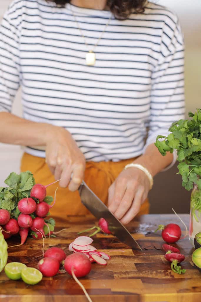 Person slicing radishes on a cutting board
