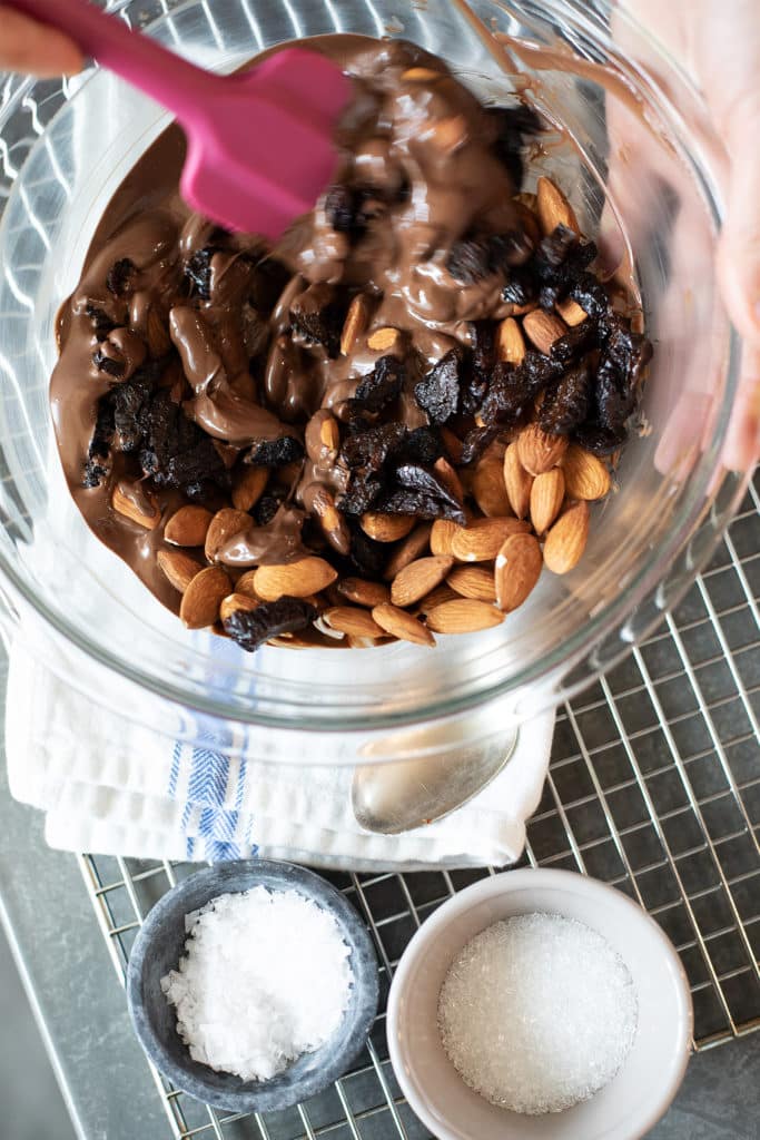 Melted chocolate in a bowl with nuts and dried fruit being stirred in