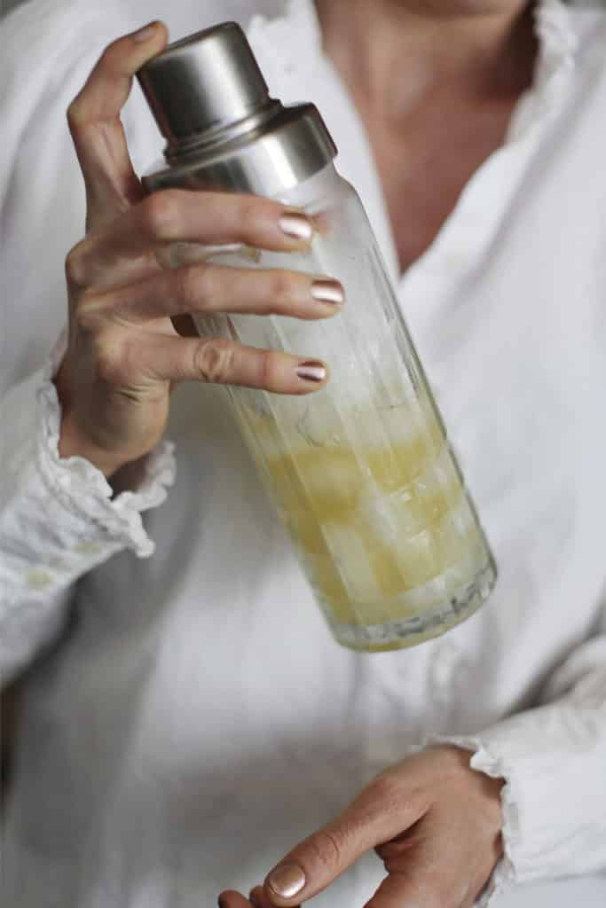 Person shaking a cocktail shaker filled with margarita
