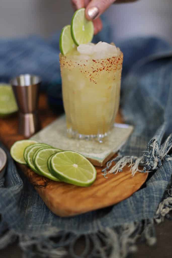 Person garnishing a margarita with sliced limes