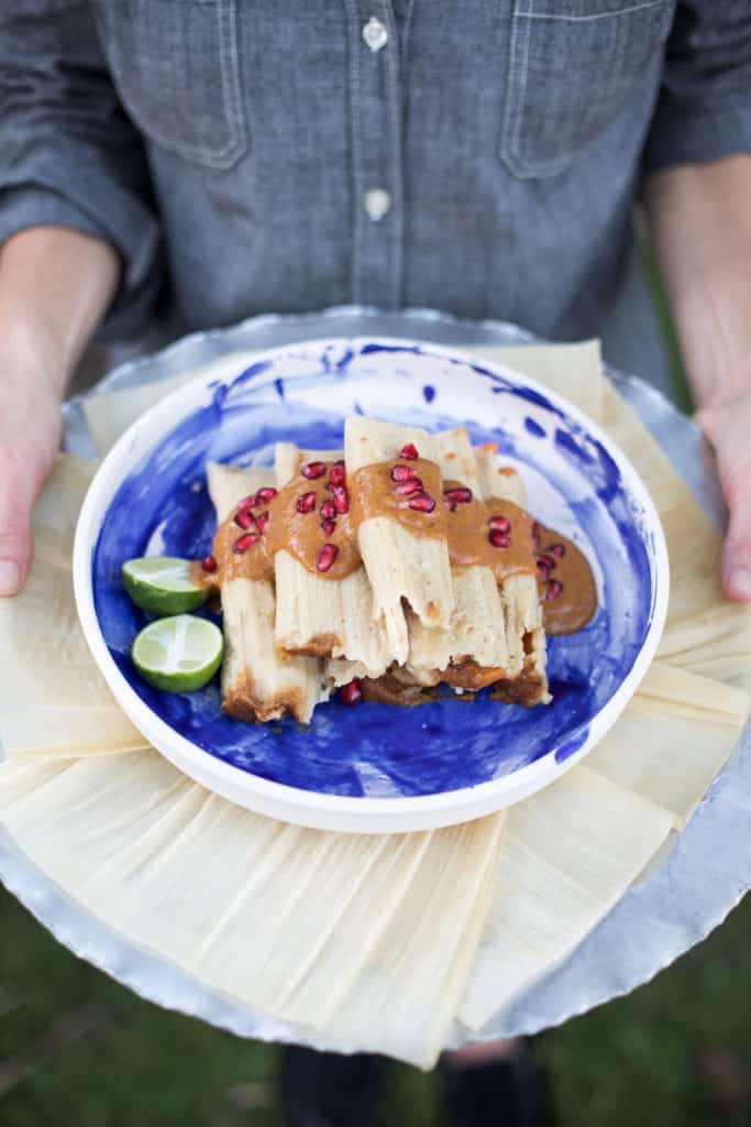 Manchamantel Tamales on a plate being served by a person in a denim shirt