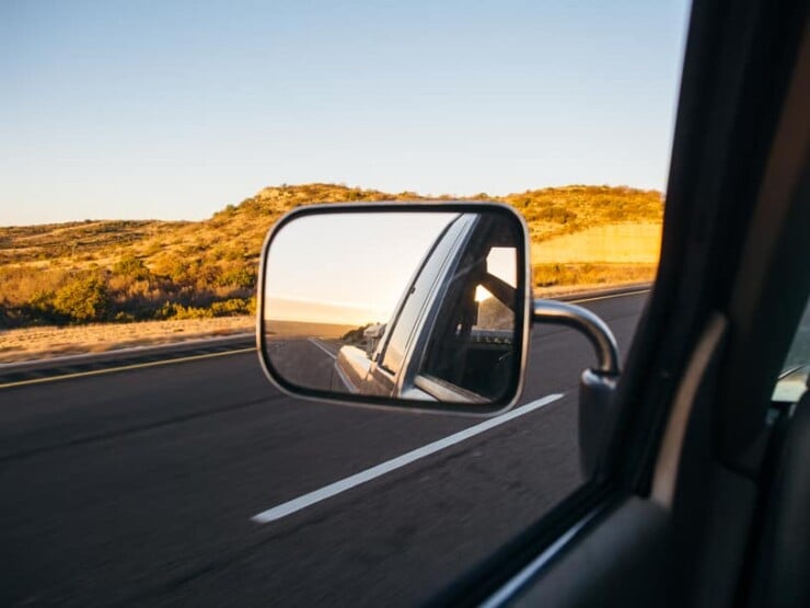 Rearview mirror reflection of road during a desert road trip