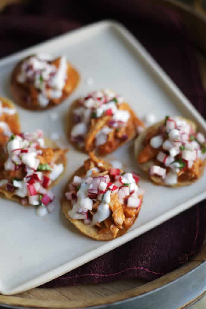 Plate of chicken tinga tostadas topped with crema
