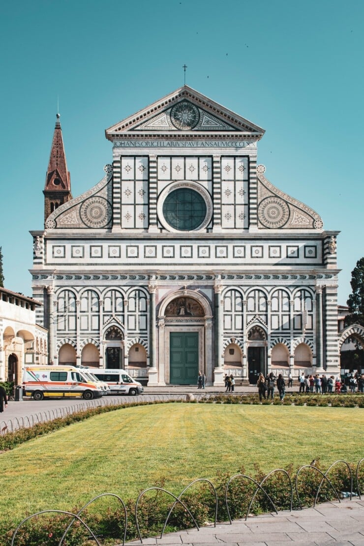View of a facade of a church with emergency vans and people out front and a lawn in the foreground