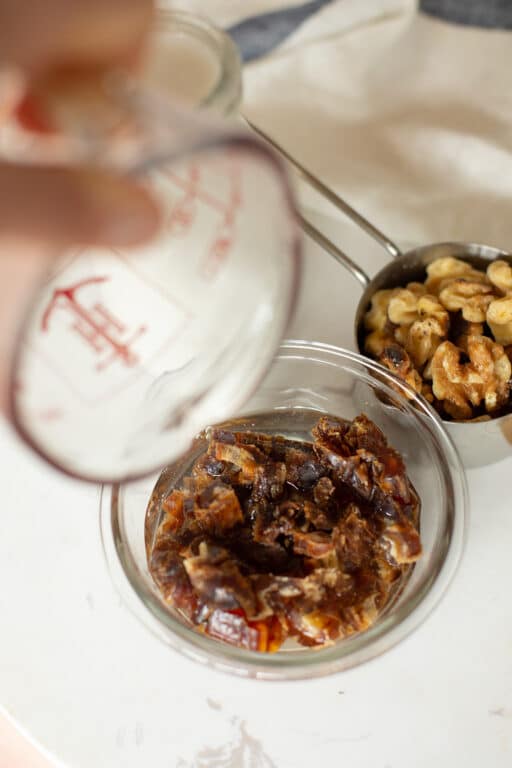 Chopped dates in a bowl with water being poured on top