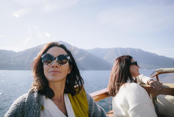 Aida Mollenkamp riding a boat on Lake Como with hills in background