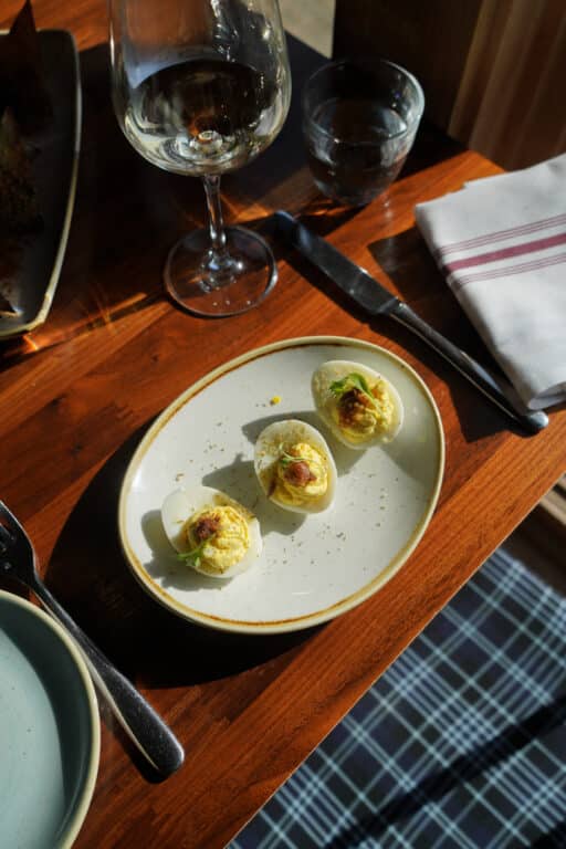 Deviled Eggs on a plate with wine anad utensils