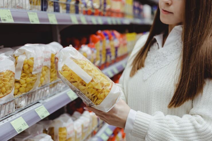 Woman at grocery store holding packaged pasta