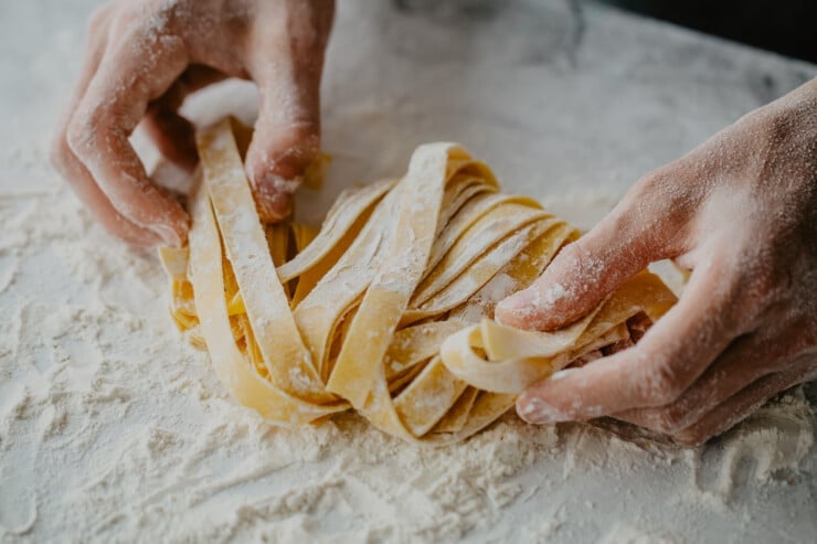 Hands making homemade fresh pasta noodles