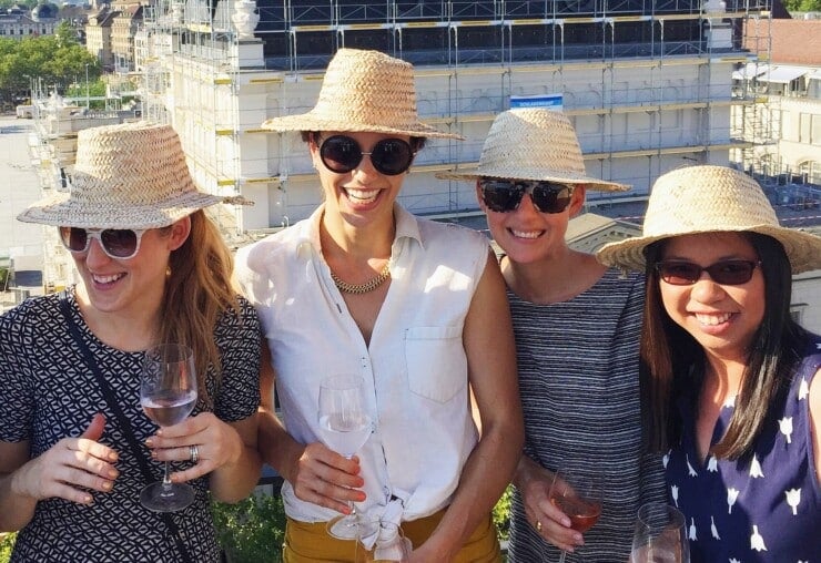 Four women with matching sun hats and glasses of rose laughing