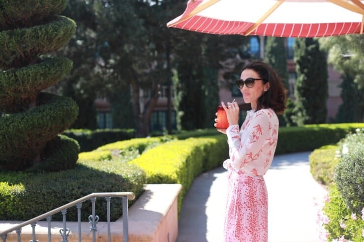 Woman sipping strawberry lemonade under an umbrella at a luxury boutique hotel in California