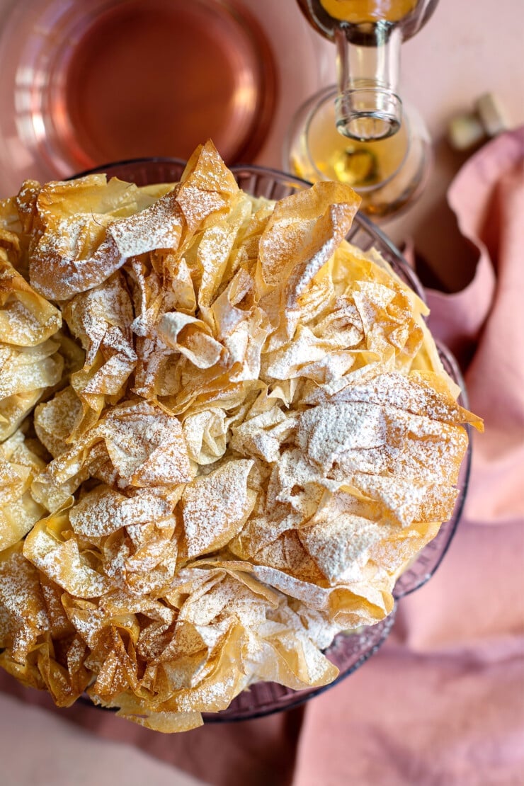 Overhead shot of a phyllo apple prune tart with glass of brandy