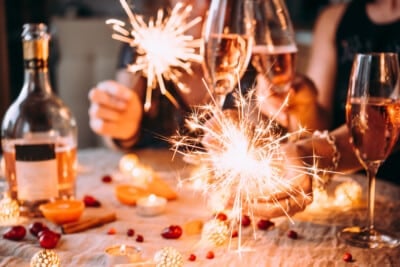 Glasses and bottle of sparkling wine with hands holding sparklers