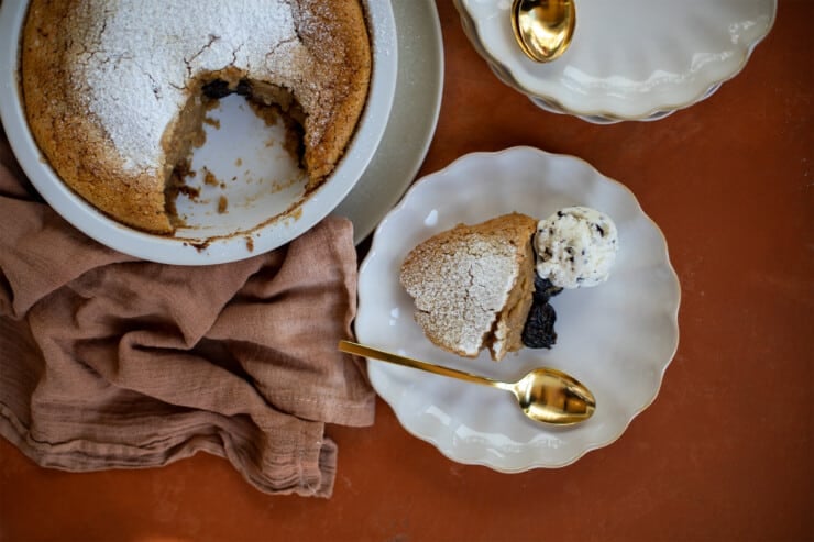 Serving of clafoutis on a plate with a spoon with a pie dish of clafoutis off to the side