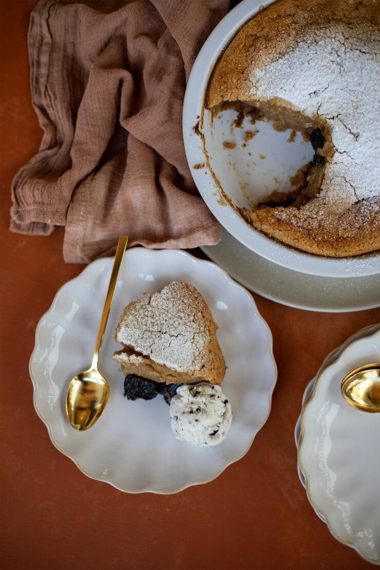 Piece of prune clafoutis on a plate with a few extra servings on the side