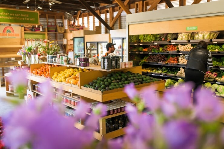 Farm stand with various containers of vegetables and produce and person in background