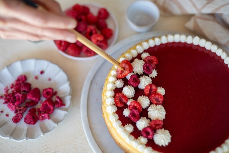 Hand garnishing cheesecake with raspberries