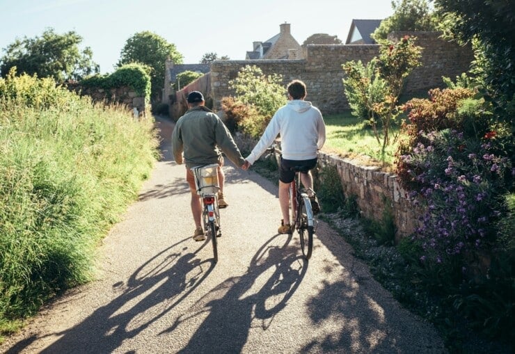 Two men holding hands while on bikes in France
