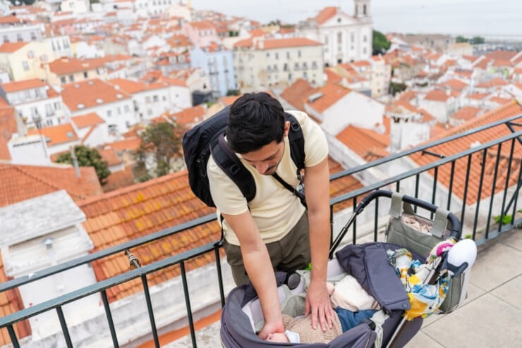 Father taking care of baby in stroller overlooking lisbon cityscape