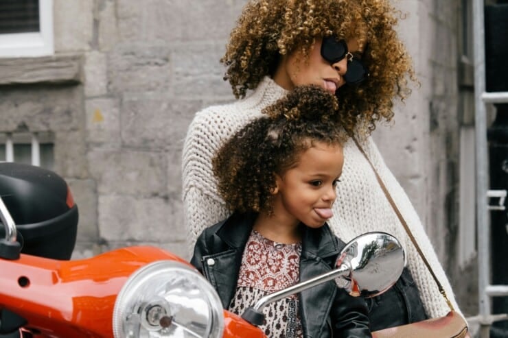 Mother and daughter posing and making faces in a mirror while on a scooter