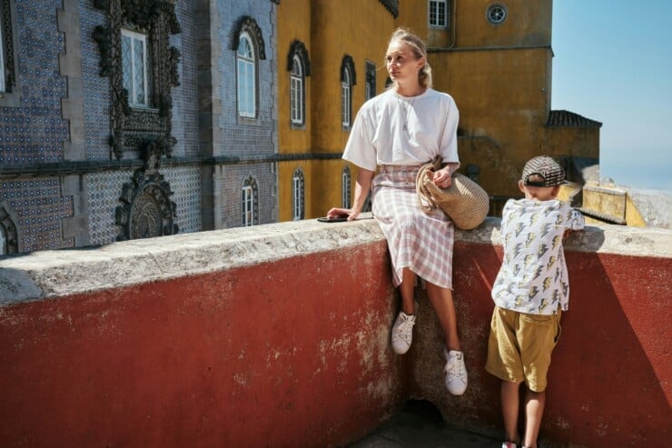 Mother and son on a terrace with a red wall overlooking Pena Palace in Sintra Portugal